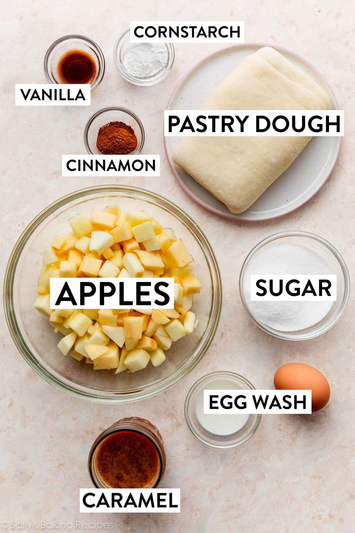 ingredients measured on peach surface including egg, sugar, cinnamon, vanilla, caramel, and pastry dough.