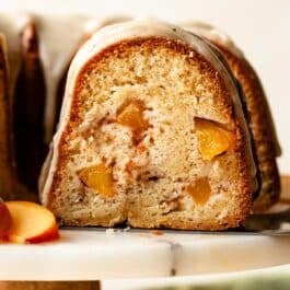 removing slice of peach Bundt cake from cake stand.