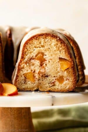 removing slice of peach Bundt cake from cake stand.