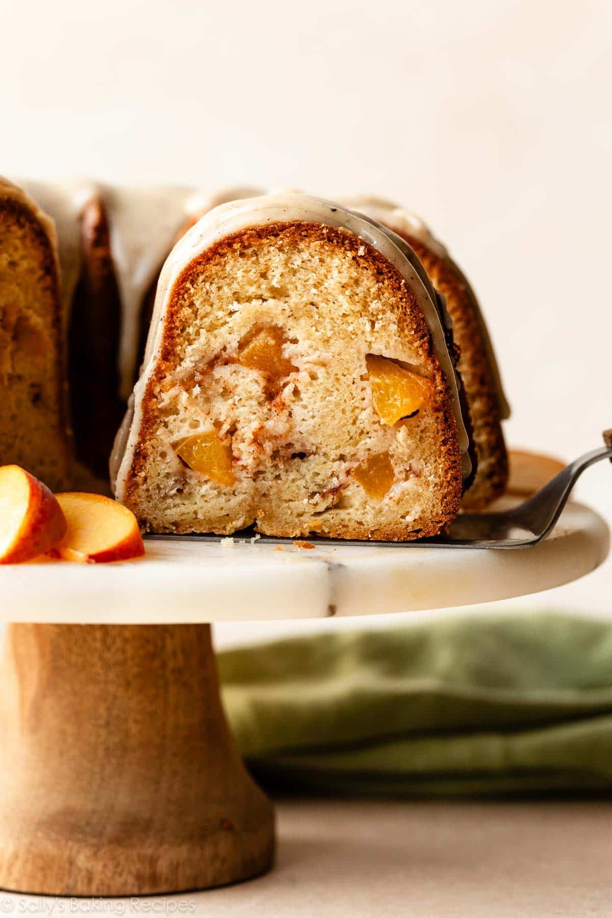 removing slice of peach Bundt cake from cake stand.