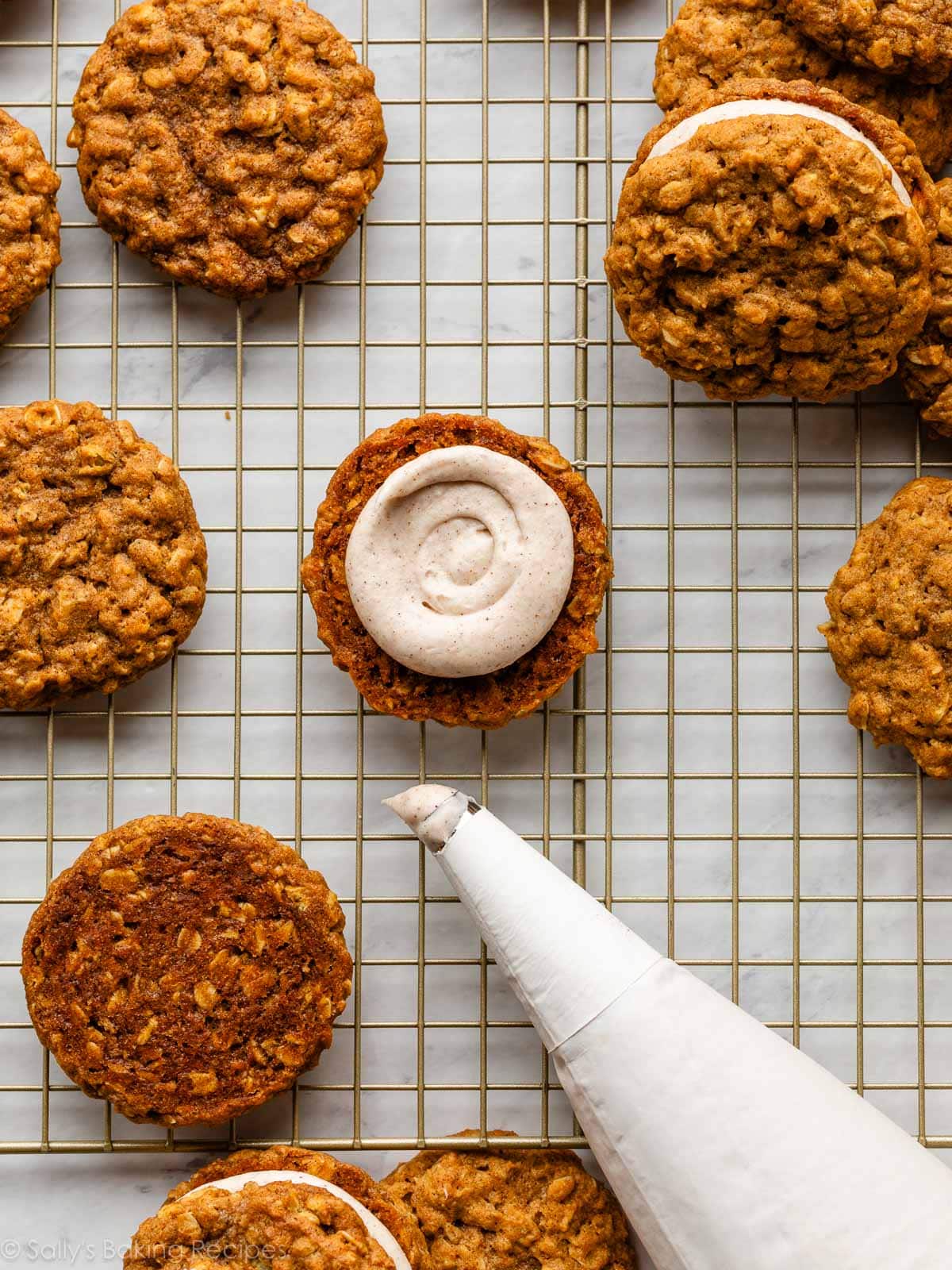 pumpkin cookie pictured on gold cooling rack with piped frosting on bottom.