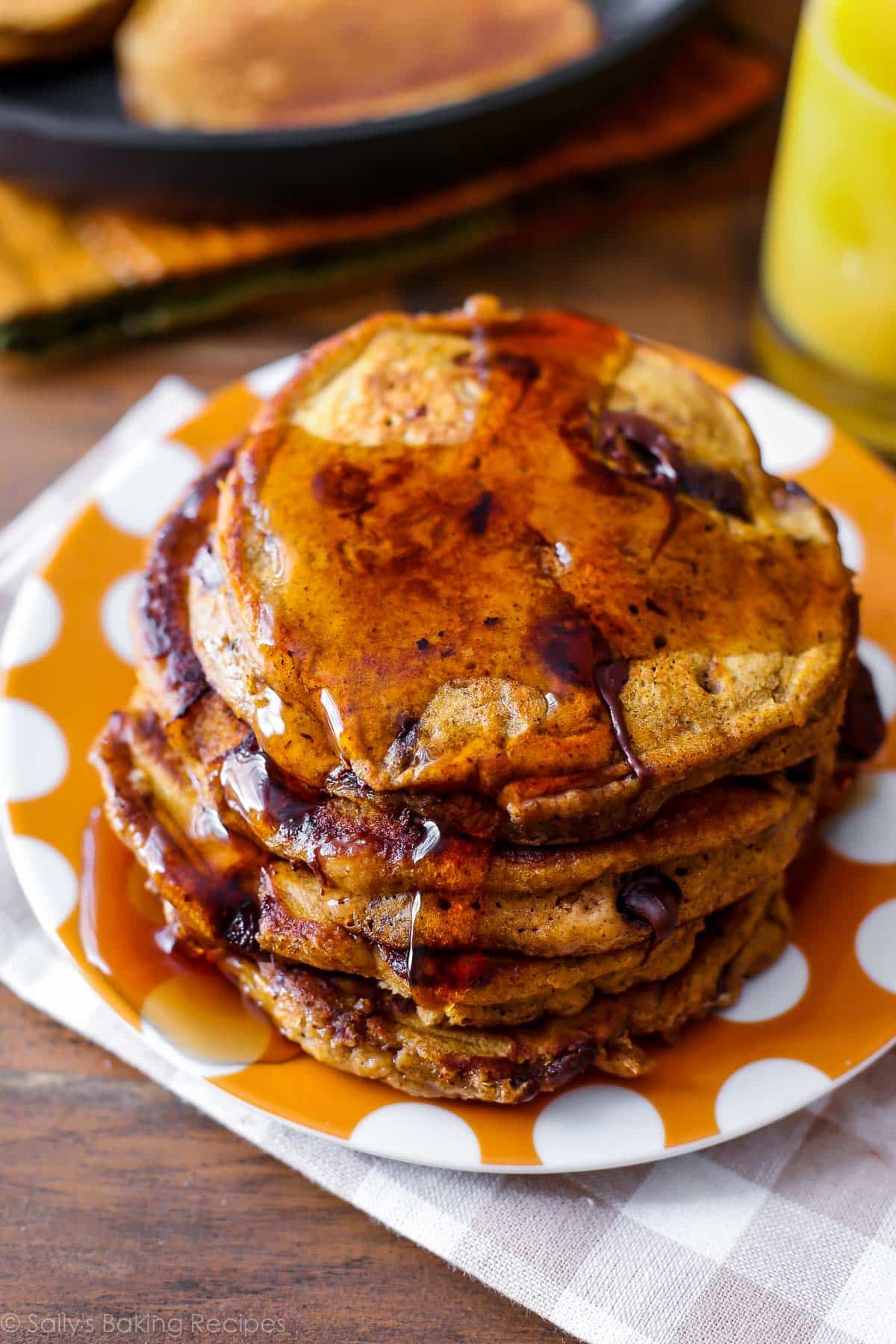 stack of pumpkin chocolate chip pancakes on orange polka dot plate.