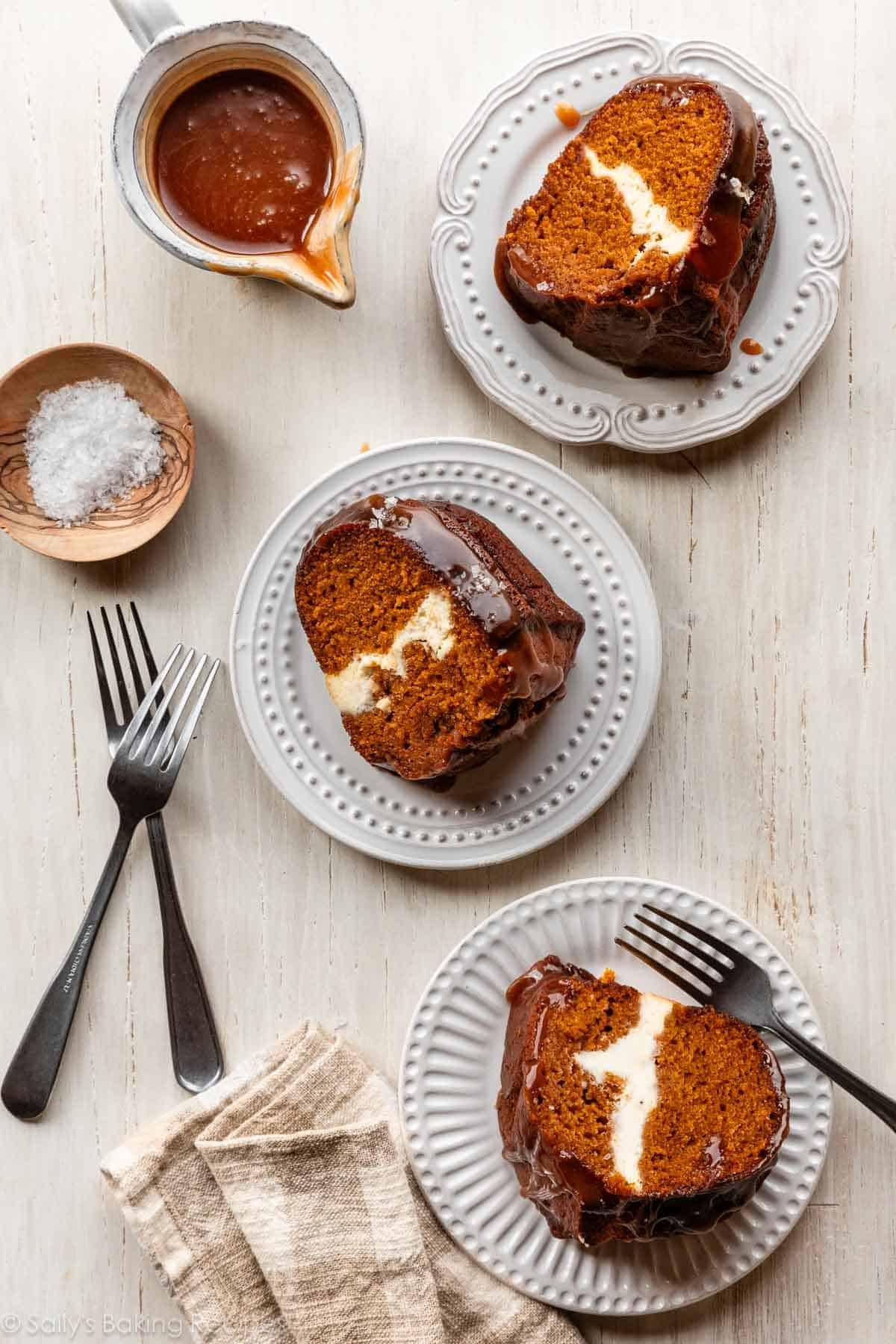 pumpkin cream cheese Bundt cake slices on white plates with salted caramel sauce.