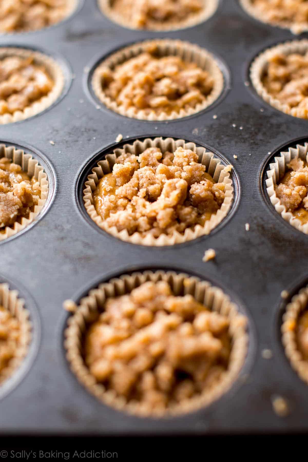 pumpkin muffin batter topped with crumb topping in a muffin pan before baking