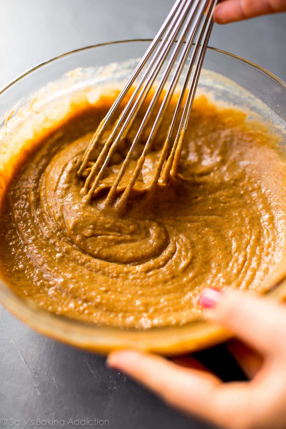 pumpkin muffin batter in a glass bowl with a whisk