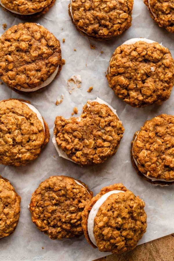 pumpkin spice oatmeal cream pies on parchment paper with 1 with bite taken out.