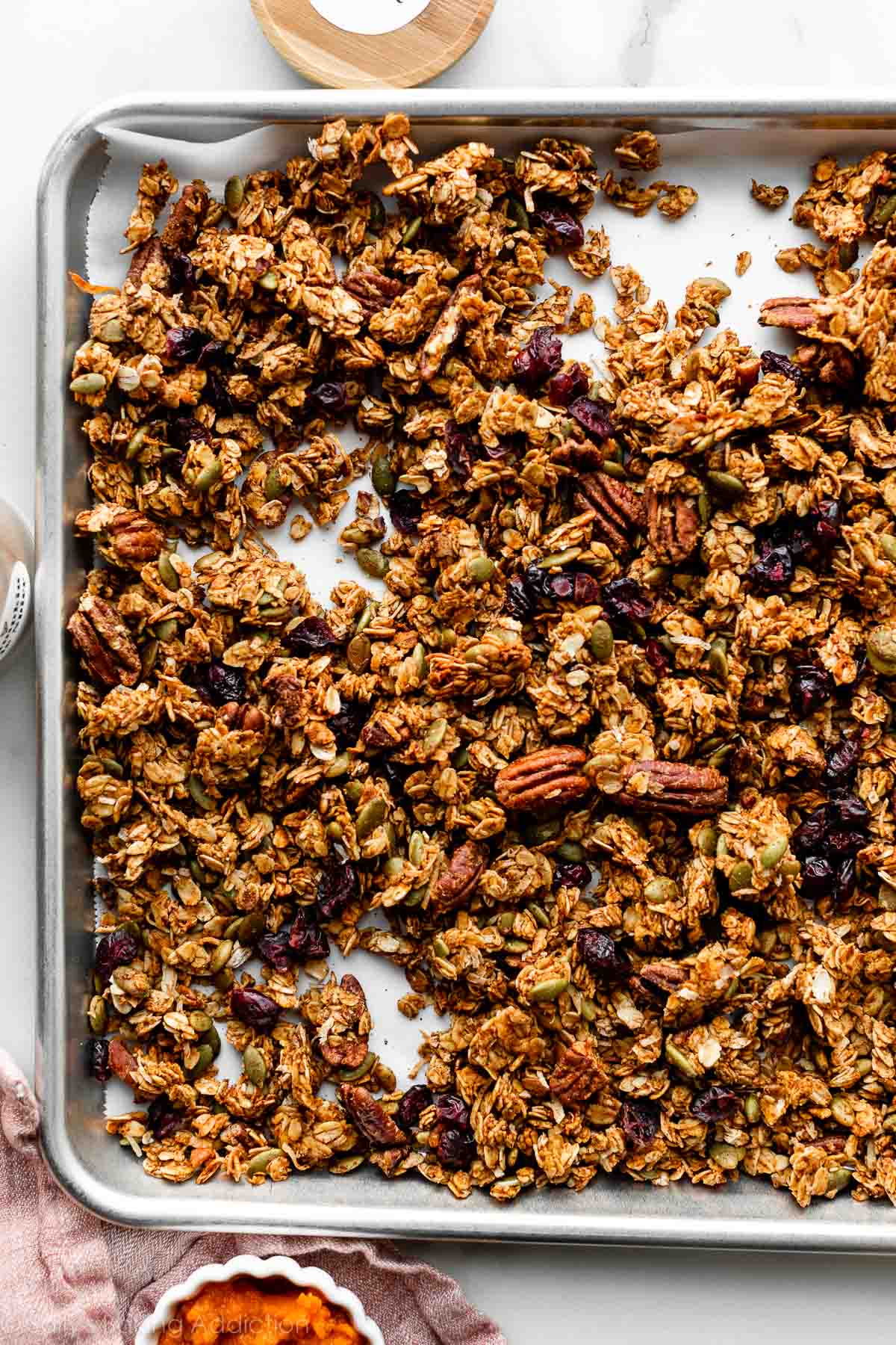 pumpkin spice granola spread on lined baking sheet.