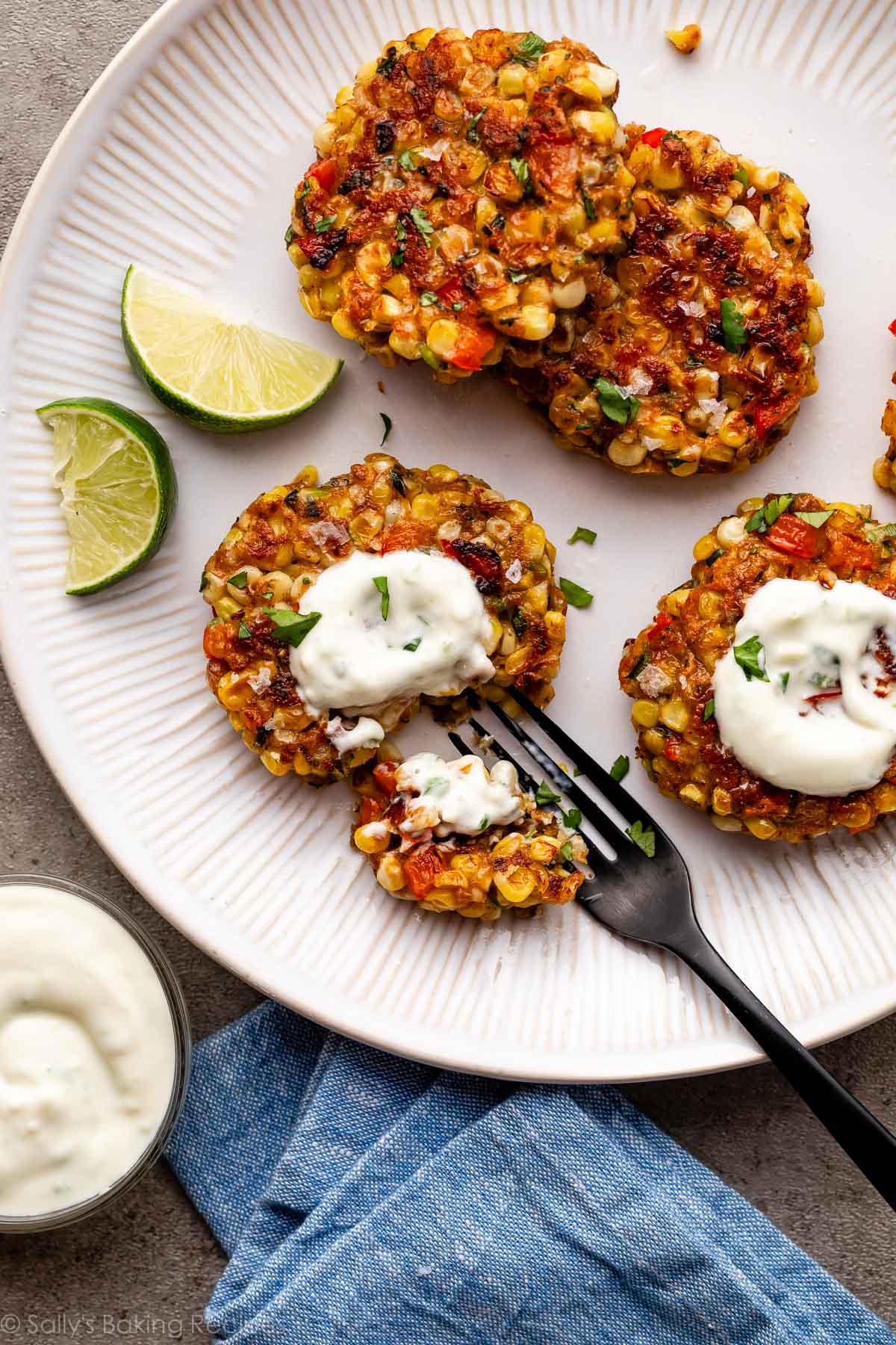 corn fritters on plate with yogurt sauce and fork.