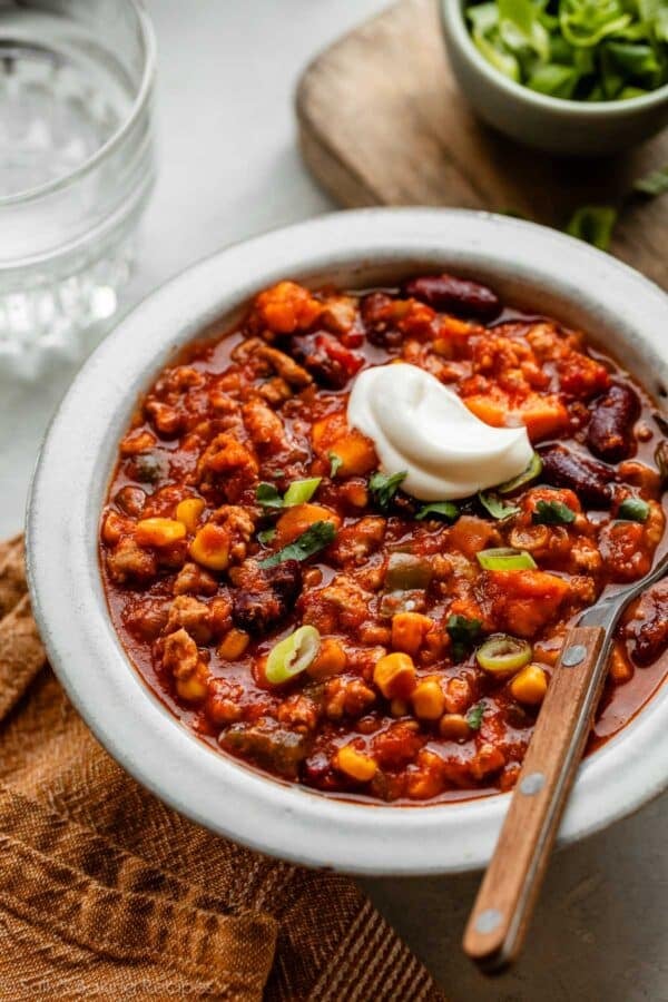 turkey sweet potato chili with sour cream on top in white bowl.