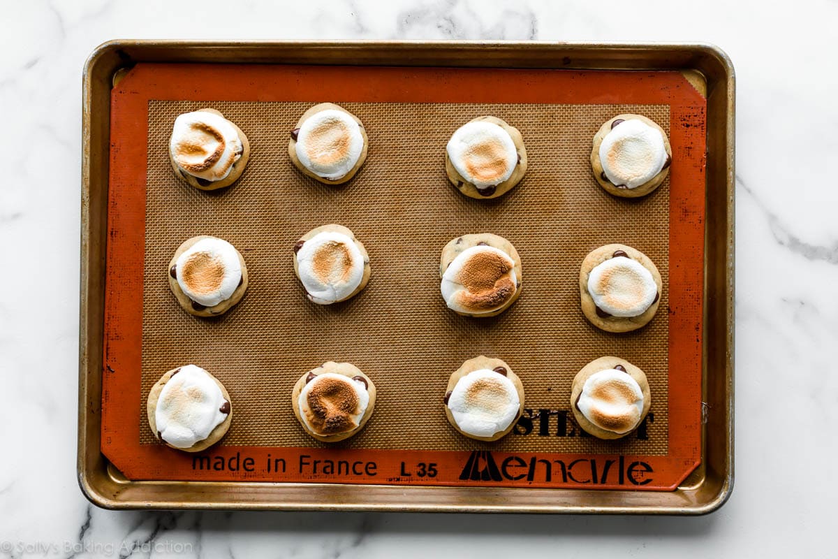 chocolate chip cookies with toasted marshmallows on top on a baking sheet