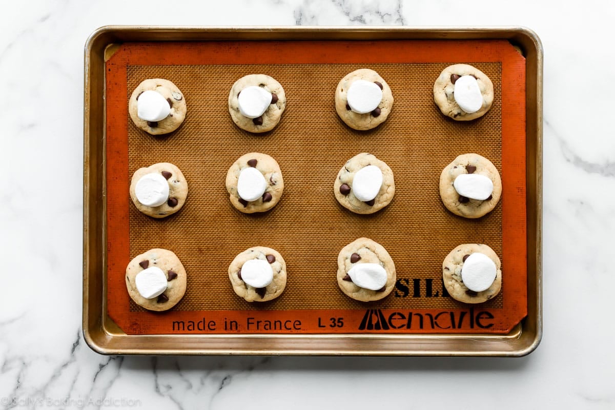 baked chocolate chip cookies with marshmallows on top on baking sheet