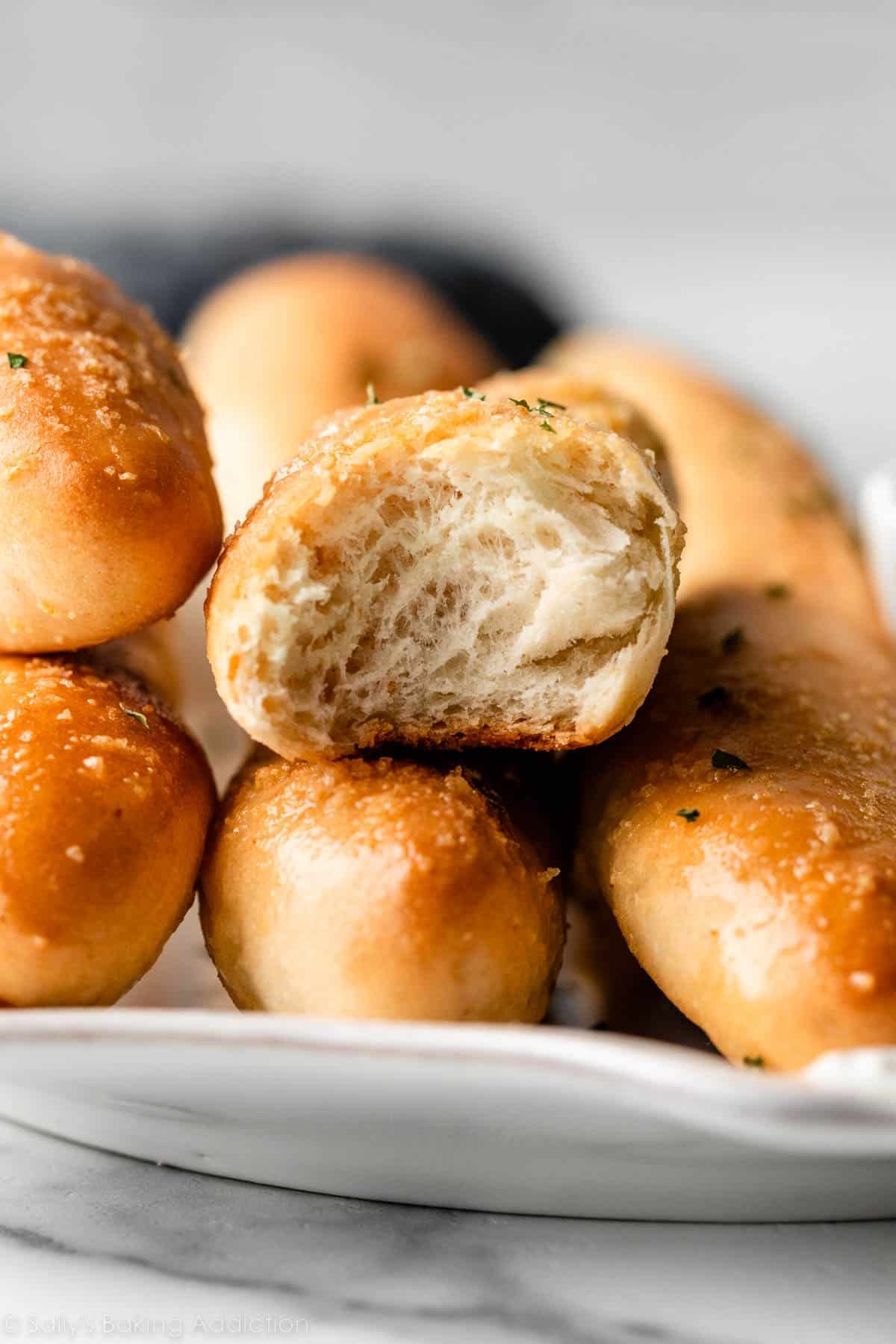 close-up photo of inside of homemade breadstick on top of other whole breadsticks.