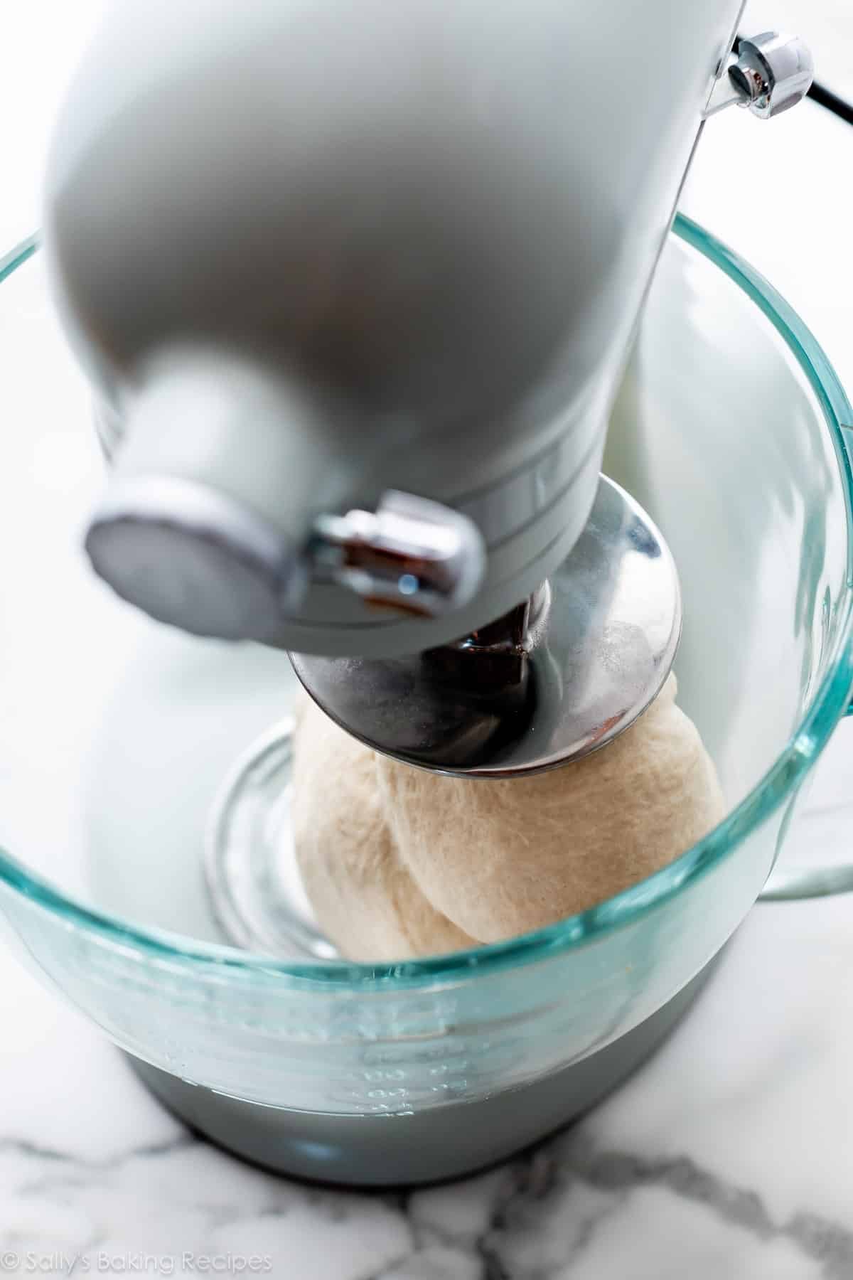 blue stand mixer kneading dough in bowl.