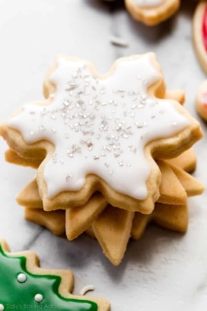 stack of snowflake sugar cookies with icing and silver sprinkles.