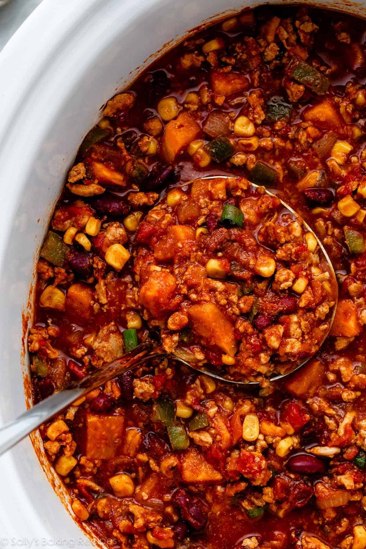 sweet potato chili with corn and kidney beans being spooned out with ladle.