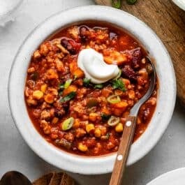 bowl of sweet potato turkey chili with spoon in it and topped with a dollop of sour cream.