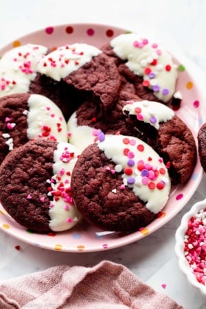 red velvet cookies dipped in white chocolate with Valentine's Day heart sprinkles on top